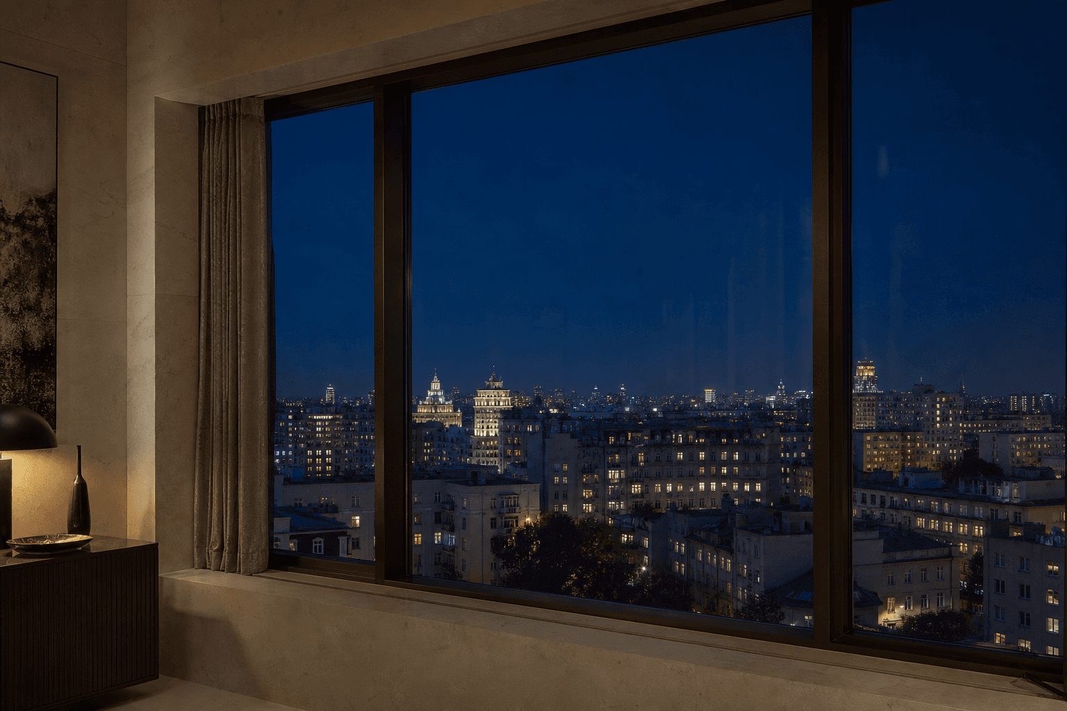 A city-center skyline framed by the windows of a residence after dark